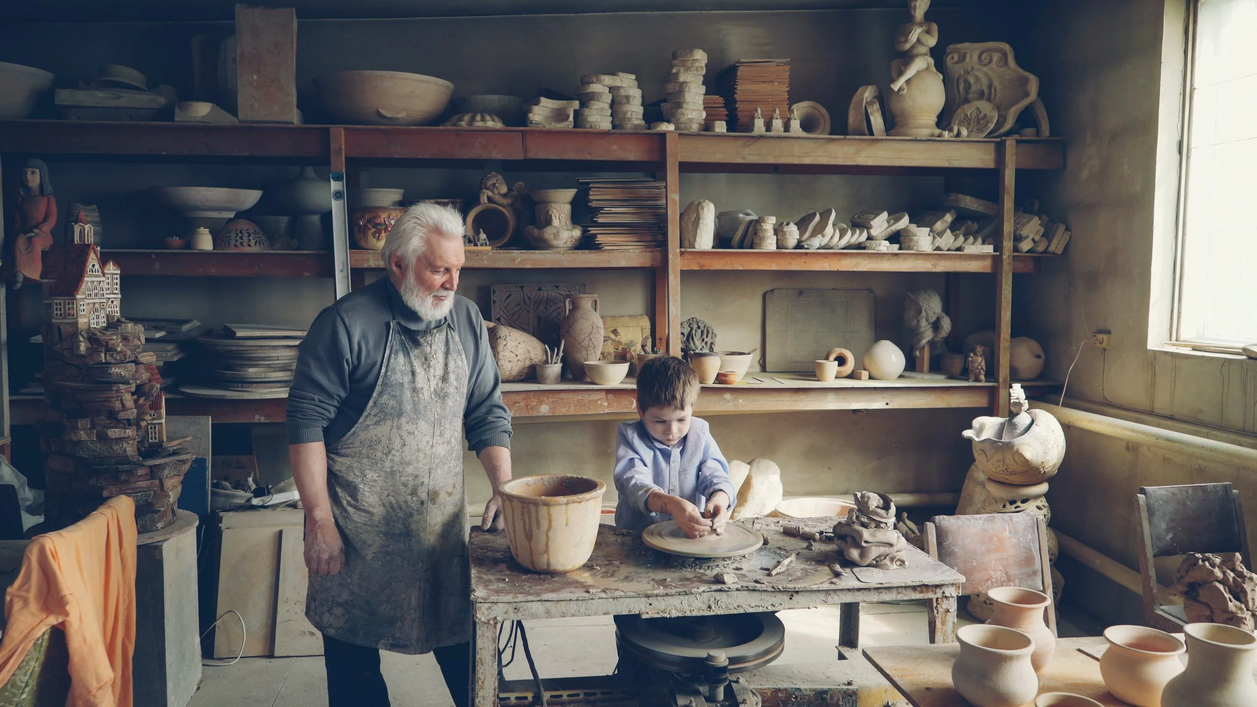 Grandfather teaching his grandson traditional pottery-making techniques in a workshop